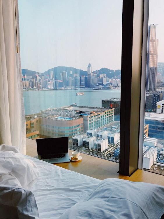 a hotel room with a view of the harbor and a bed and a laptop