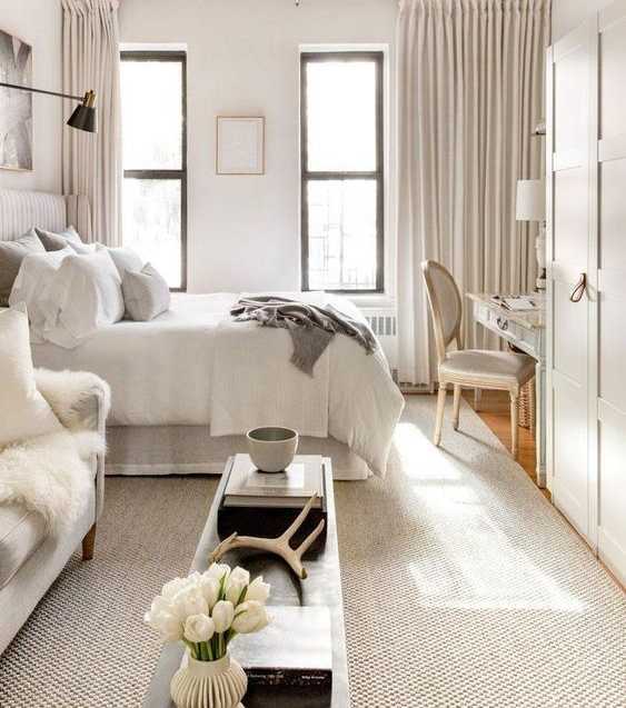 A white bedroom with a large bed and a chair.