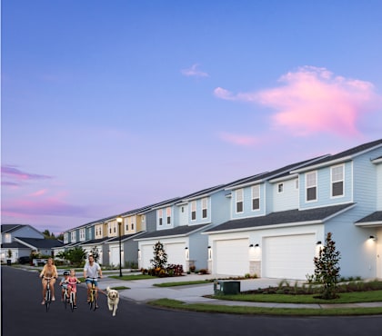 A row of houses with people riding bikes in front.
