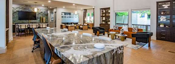 A large marble table with chairs is in the center of a spacious room.