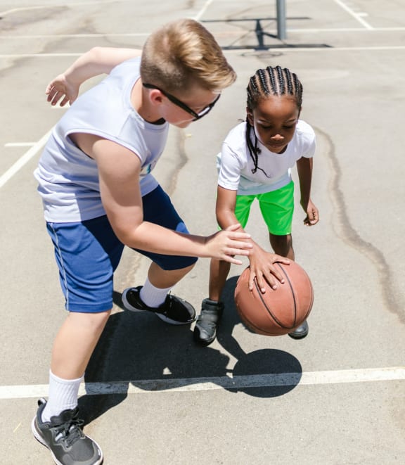 a young boy and girl playing basketball on a basketball court