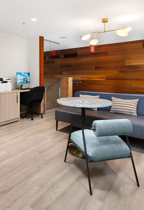 A modern office space with a blue couch and a desk with a computer.
