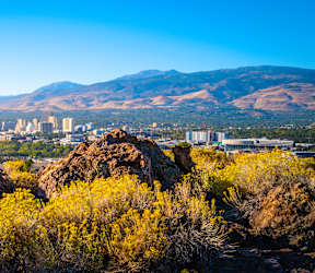 A cityscape with a mountain in the background and buildings lit up in the foreground.