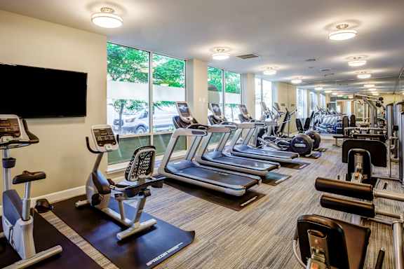 A gym with a variety of equipment including treadmills, stationary bikes, and weight machines.