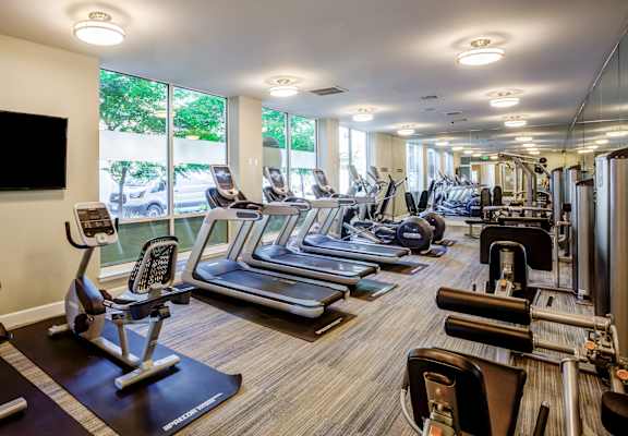 A gym with a variety of equipment including treadmills, stationary bikes, and weight machines.