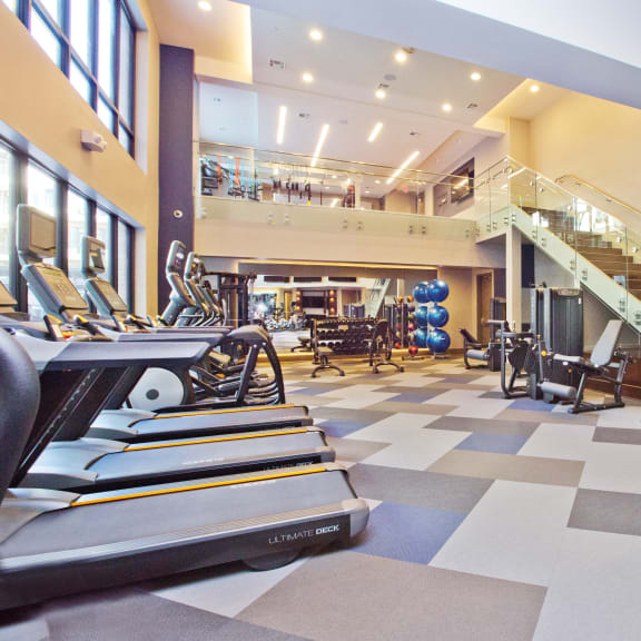 a gym with cardio machines and a staircase