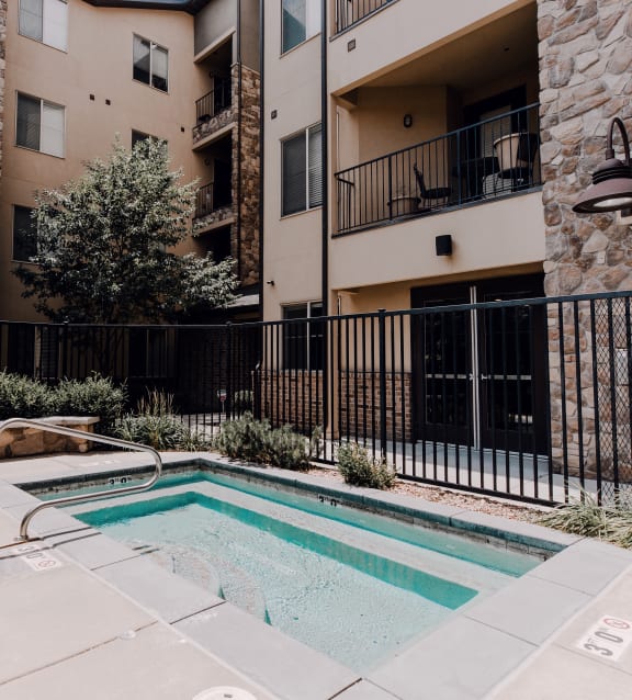 an apartment swimming pool with an apartment building in the background