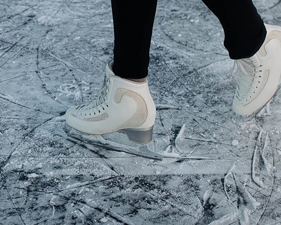 A person is walking on a frozen surface wearing white shoes.