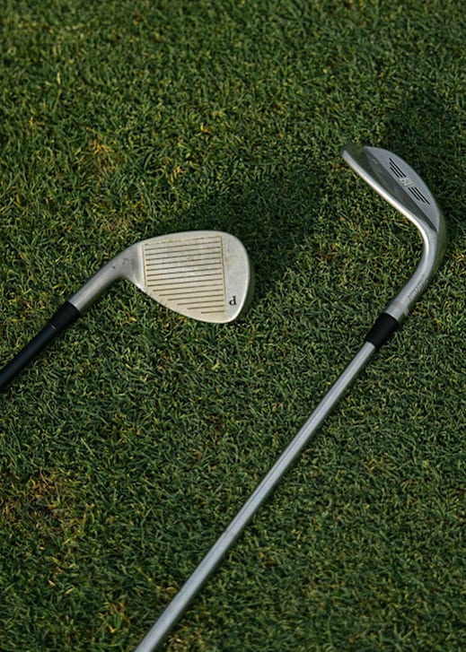 A golf club and a golf ball on a grassy surface.