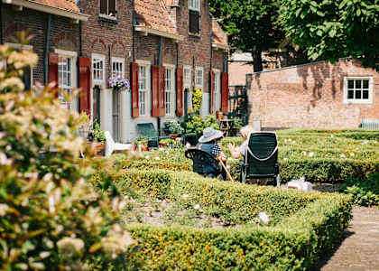 A man is sitting on a chair in a garden.