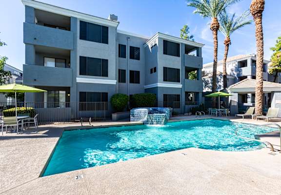 A large swimming pool in front of a multi-story apartment building.