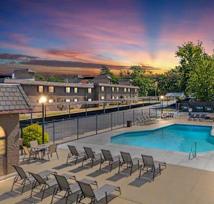 A pool surrounded by chairs and a fence.