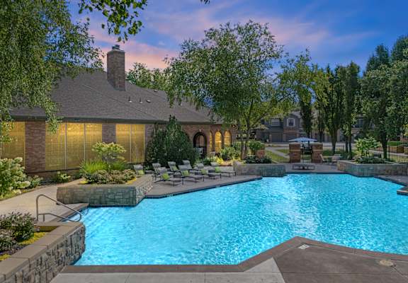 A large swimming pool in front of a house surrounded by trees.