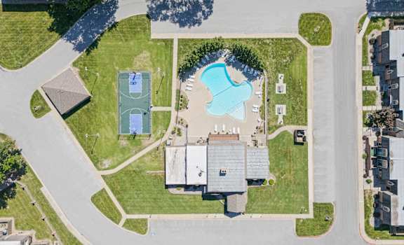 A large building is surrounded by a grassy area and a pool.