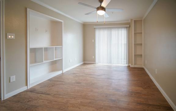 an empty living room with a large window and a ceiling fan