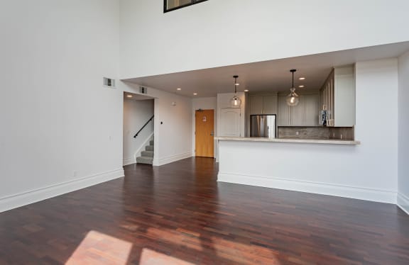 an empty living room and kitchen with wood floors and white walls at Vendome Place, San Jose