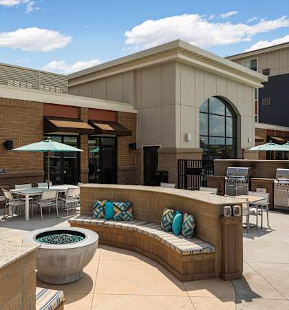 A patio area with a bench, chairs, and a table.
