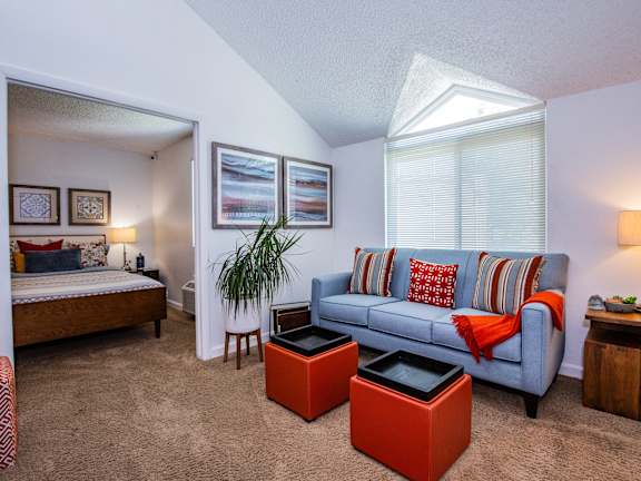 A living room with a blue couch and a red ottoman.