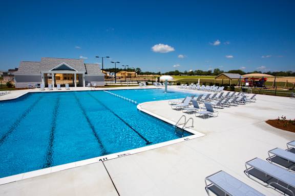 A large swimming pool with lounge chairs and a building in the background.
