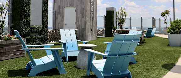 a row of blue lounge chairs and tables on a roof top patio with a building