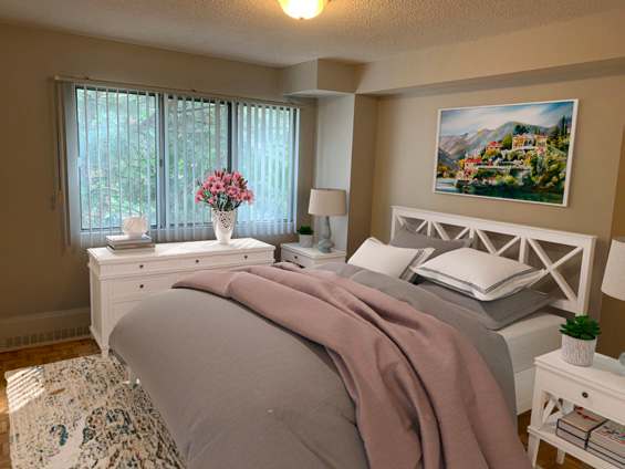 A bedroom with a bed, nightstand, and a painting on the wall.
