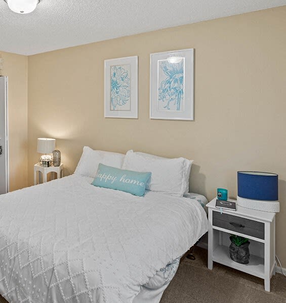 a bedroom with a white bed and two pictures on the wall
