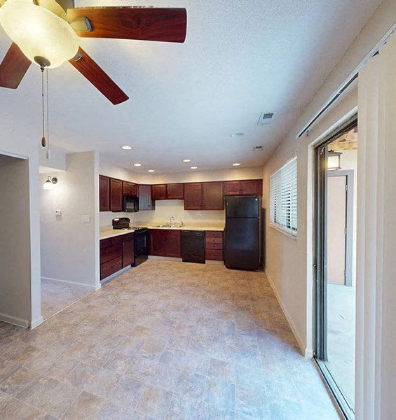 a empty kitchen with a refrigerator and a ceiling fan