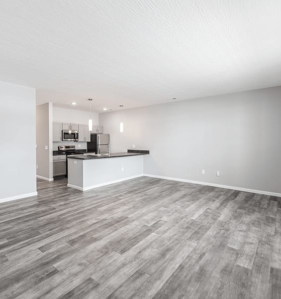 a spacious living room with a kitchen in the background