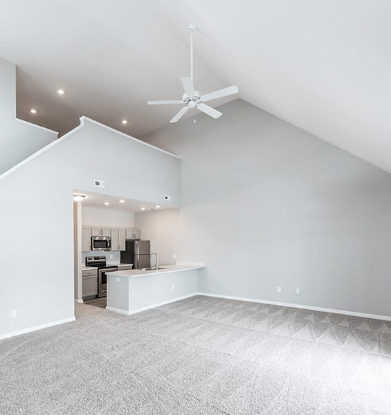 a living room with a vaulted ceiling and a kitchen in the background