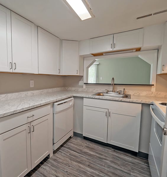 an empty kitchen with white cabinets and a sink