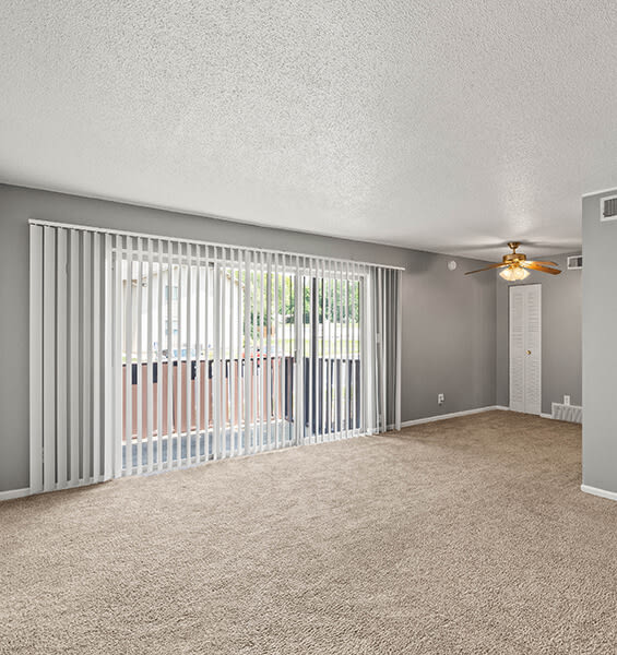 an empty living room with blinds and a ceiling fan