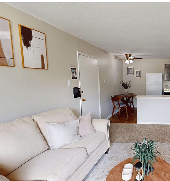 A living room with a white couch and a plant on the coffee table.