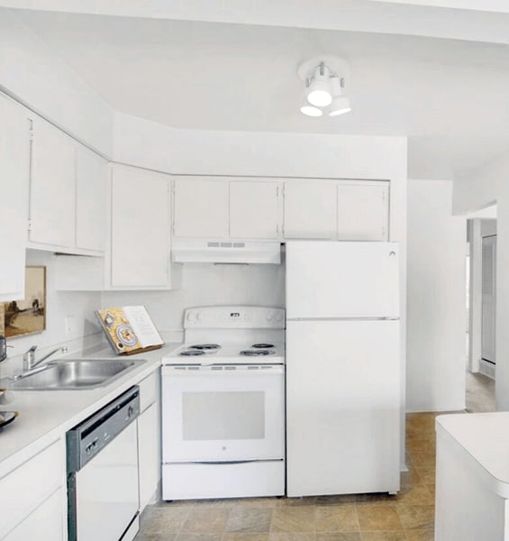A white kitchen with a sink, stove, and refrigerator.