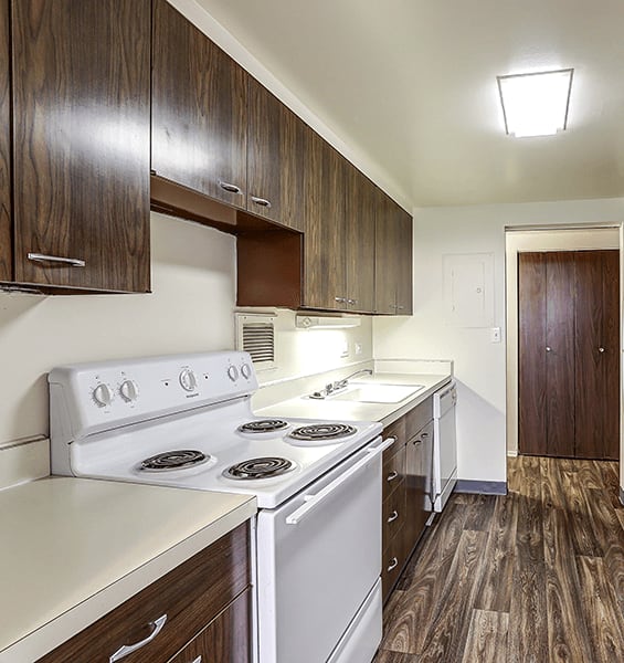 A kitchen with a white stove top oven and wooden cabinets.