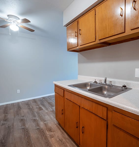 A kitchen with wooden cabinets and a ceiling fan.