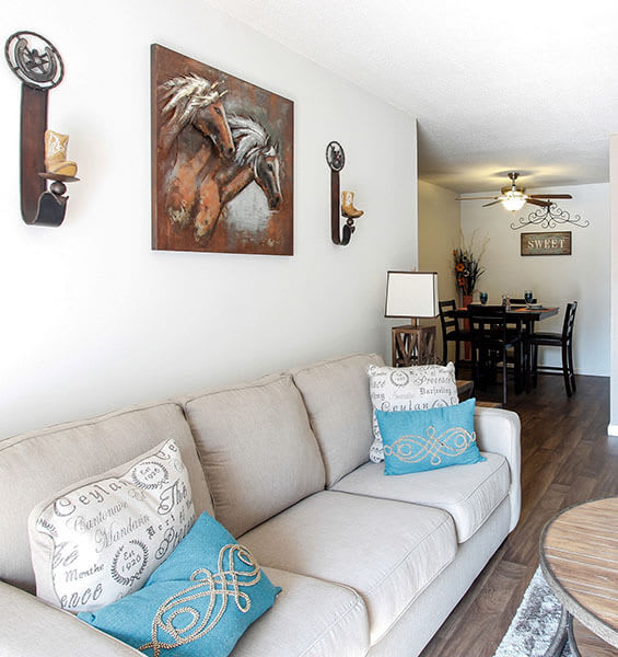 A living room with a couch and a painting of a horse on the wall.