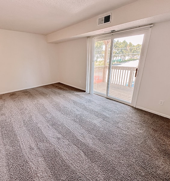 an empty living room with a sliding glass door to a balcony