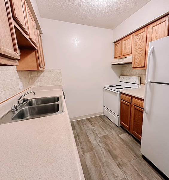 an empty kitchen with a sink and a refrigerator