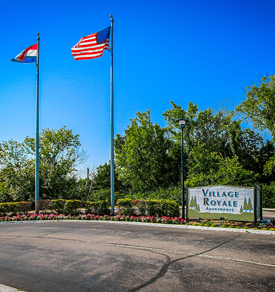 two flags flying above a sign for village royale