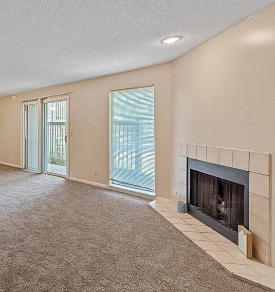 an empty living room with a fireplace and a sliding glass door