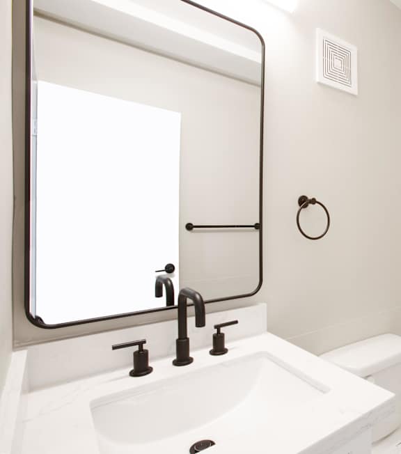 A modern white bathroom with a sink, mirror, and tiled shower