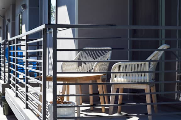 Two chairs and a table are on a balcony.