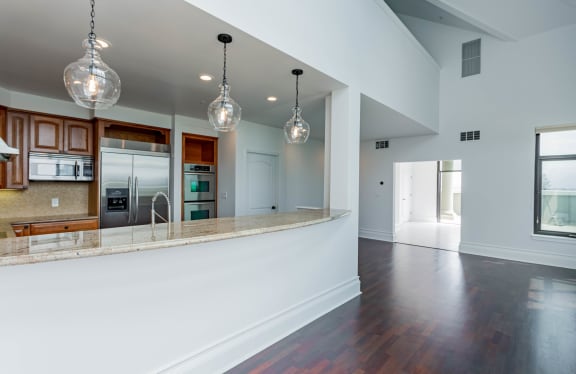 an open kitchen and living room with white walls and wood floors at Vendome Place, San Jose