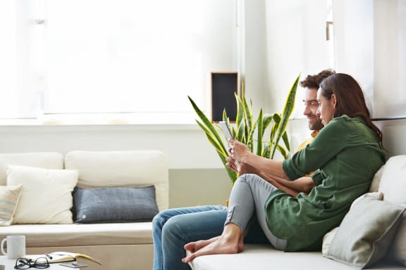 Man and Woman Sitting on Couch Looking at Phone