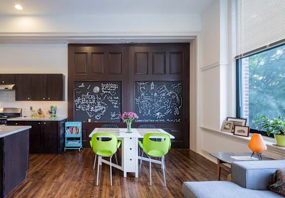 A kitchen with a chalkboard wall and a dining table with chairs.