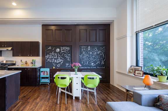 A kitchen with a chalkboard wall and a dining table with chairs.