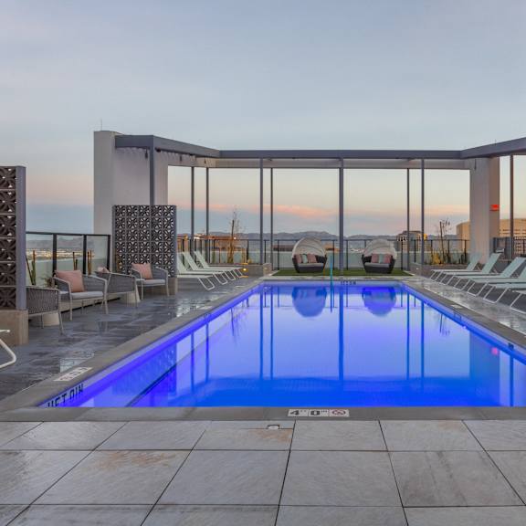 A large outdoor swimming pool with lounge chairs and a glass enclosure.