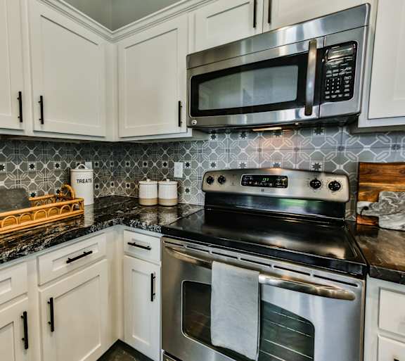 A kitchen with a black granite countertop and white cabinets.