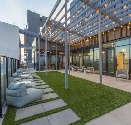 A modern outdoor seating area with white bean bag chairs and a metal pergola.