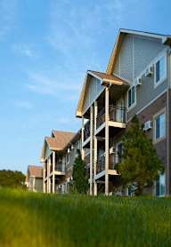 A row of apartment buildings with balconies and trees in front.